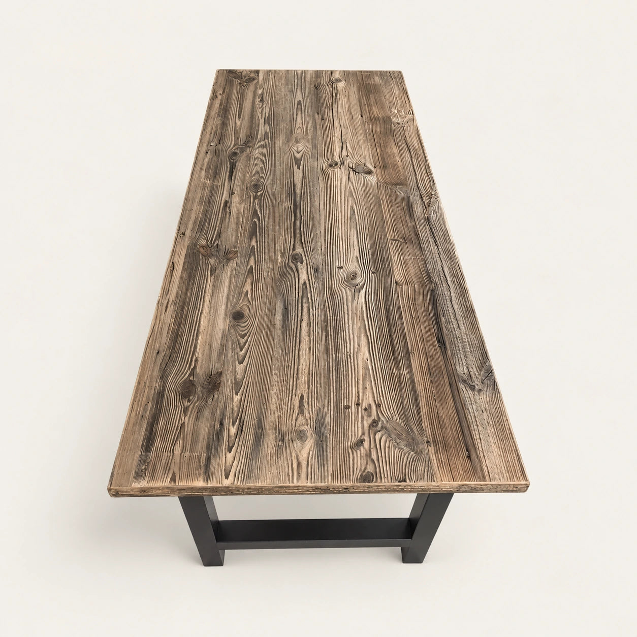 Table Alpine vue en plongée depuis une extrémité sur fond clair, avec plateau texturé et piètements noirs.